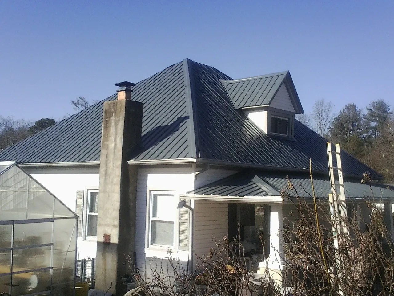 Dark blue standing seam metal roof on a white farmhouse with dormer — Slate & Tile Roof Repair by Roofing Brothers in Nappanee