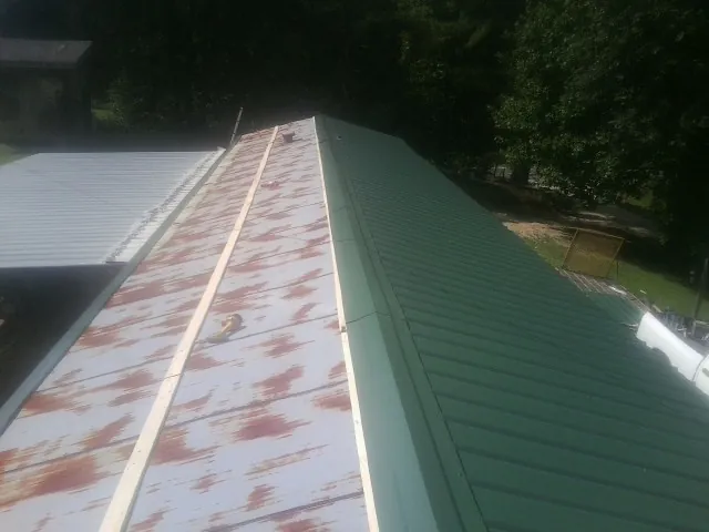 Old rusted panels beside newly installed green metal roofing — Wind Damage Roof Repair by Roofing Brothers in Nappanee