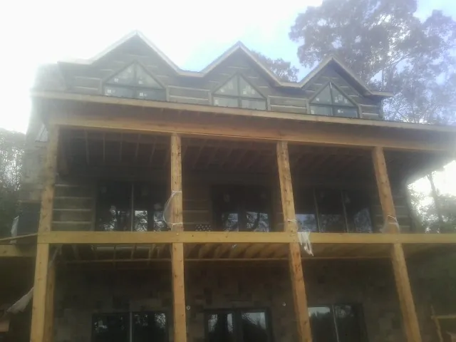 Dormers and porch framing on a large log home under construction — Roof Coating work by our crew in Nappanee