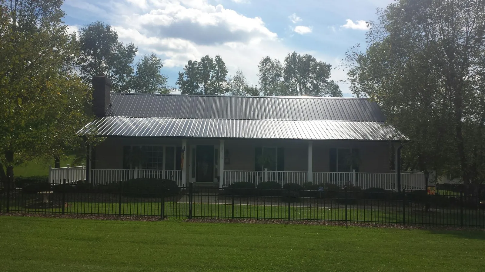 Gray metal roof on a brick ranch with a full width front porch — Gutter Guard Installation work by our crew in Nappanee