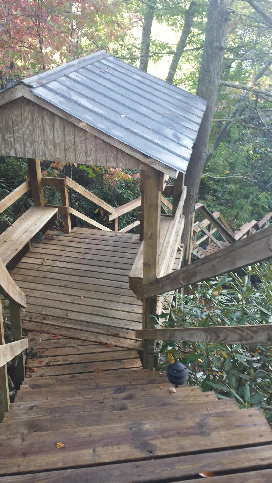 Metal roofed shelter over wooden steps on a wooded walkway — Skylight Repair & Installation work by our crew in Nappanee
