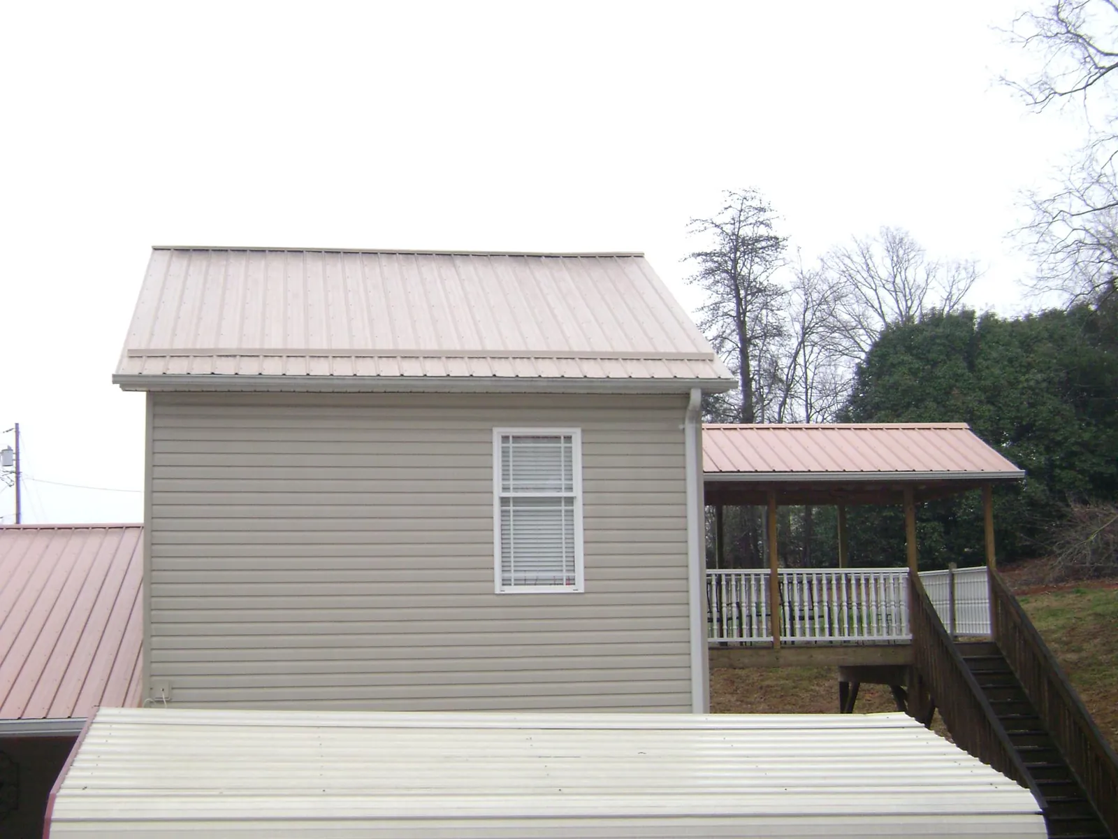 Tan metal roofs on a two story addition and attached porch, from a Roof Replacement job in Nappanee