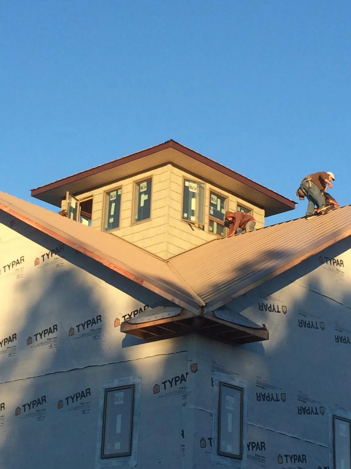 Roofers working around a rooftop cupola on a new metal roof at sunset — Roof Waterproofing in Nappanee by Roofing Brothers